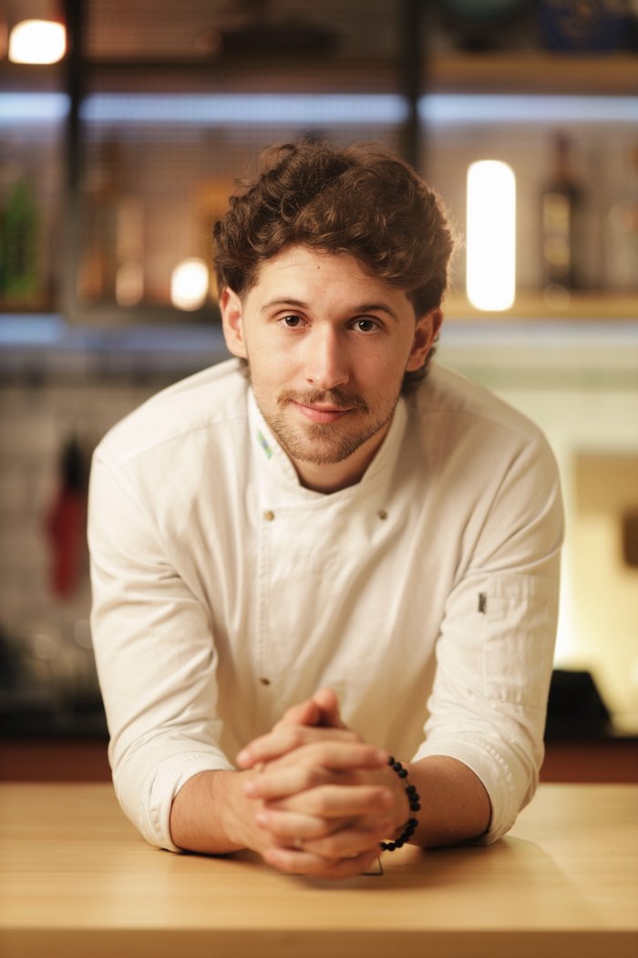 Cheff Otto apoiado no balcão da cozinha, sorrindo