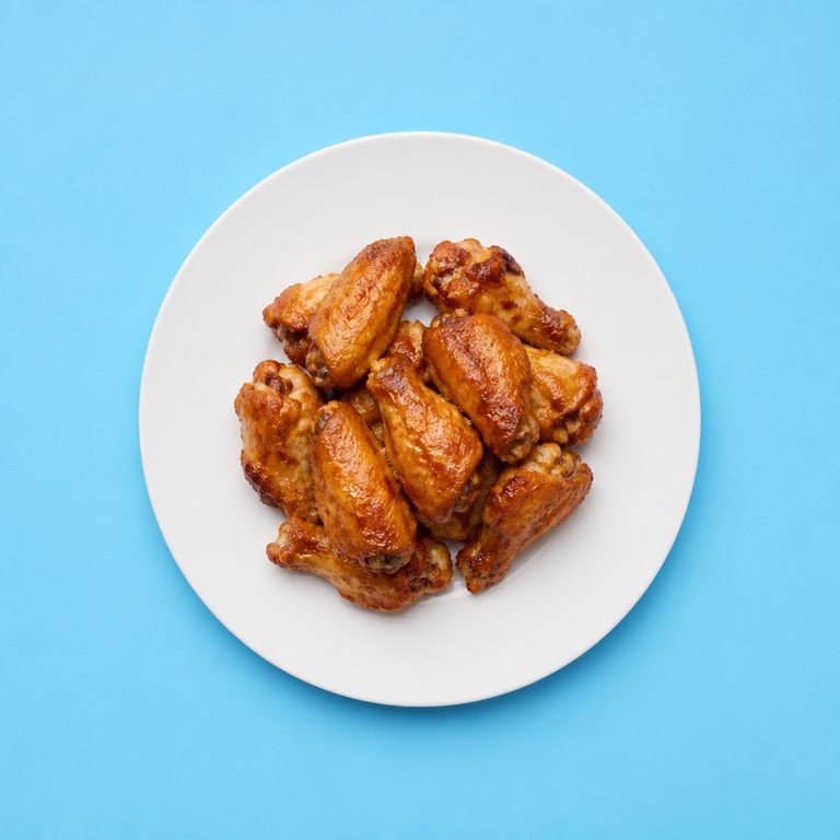 Asinha de Frango em prato branco, fotografia de cima com fundo colorido