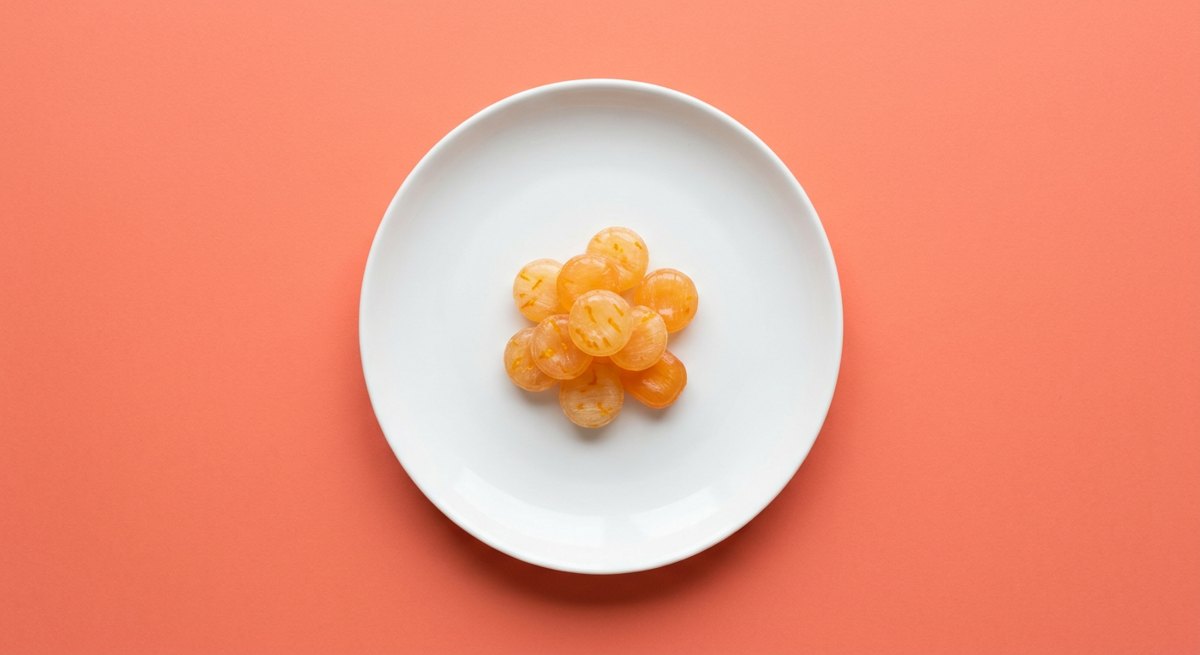 Bala de Laranja em prato branco, fotografia de cima com fundo colorido