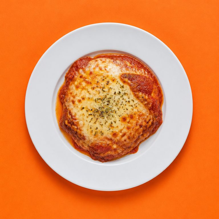 Bife à Parmigiana em prato branco, fotografia de cima com fundo colorido