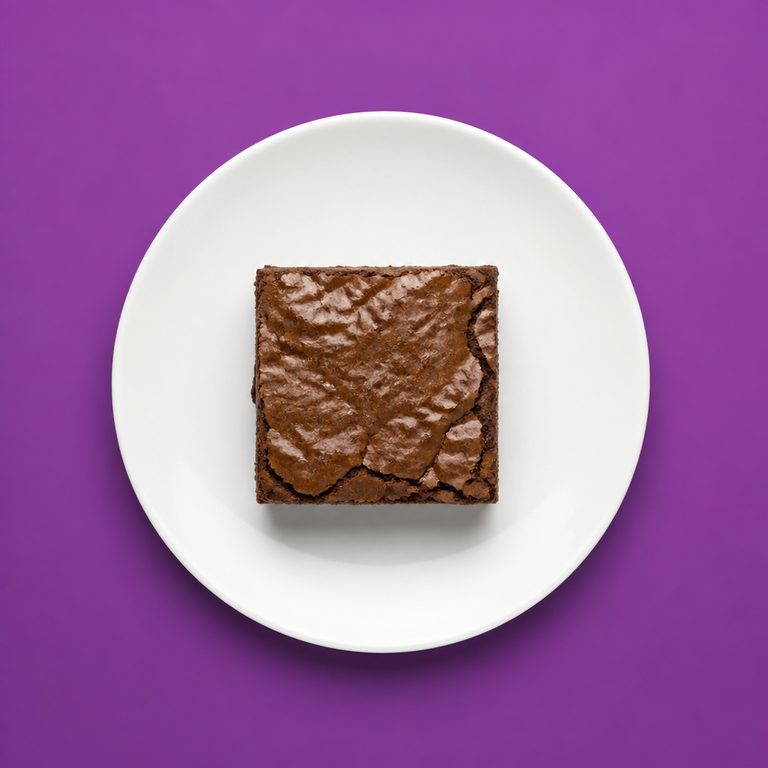 Brownie em prato branco, fotografia de cima com fundo colorido