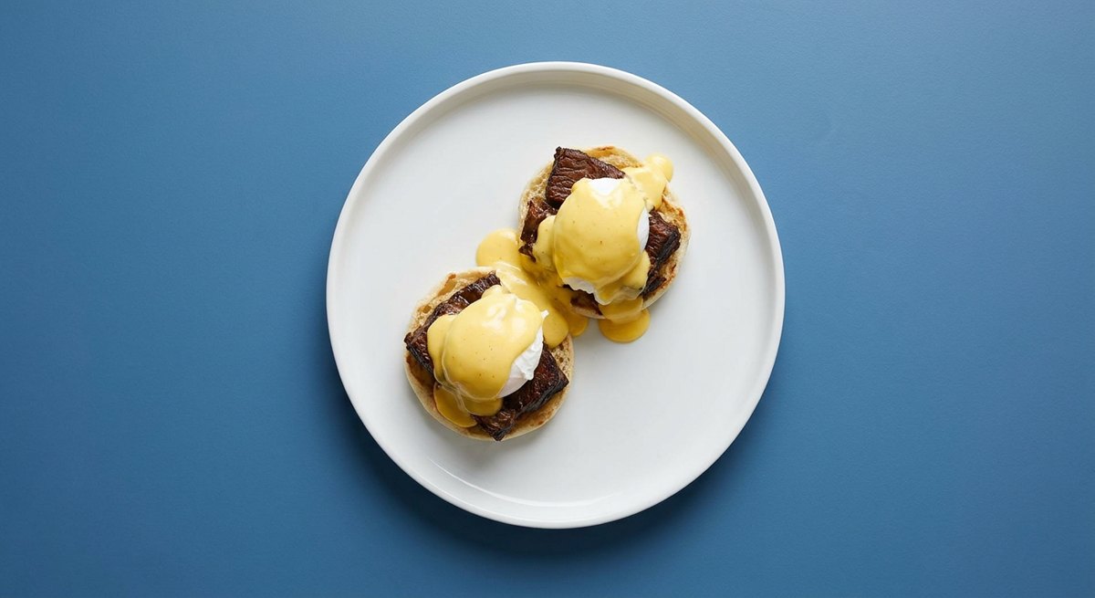 Eggs Benedict de Costela em prato branco, fotografia de cima com fundo colorido
