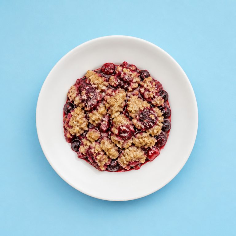 Fruit Crumble em prato branco, fotografia de cima com fundo colorido