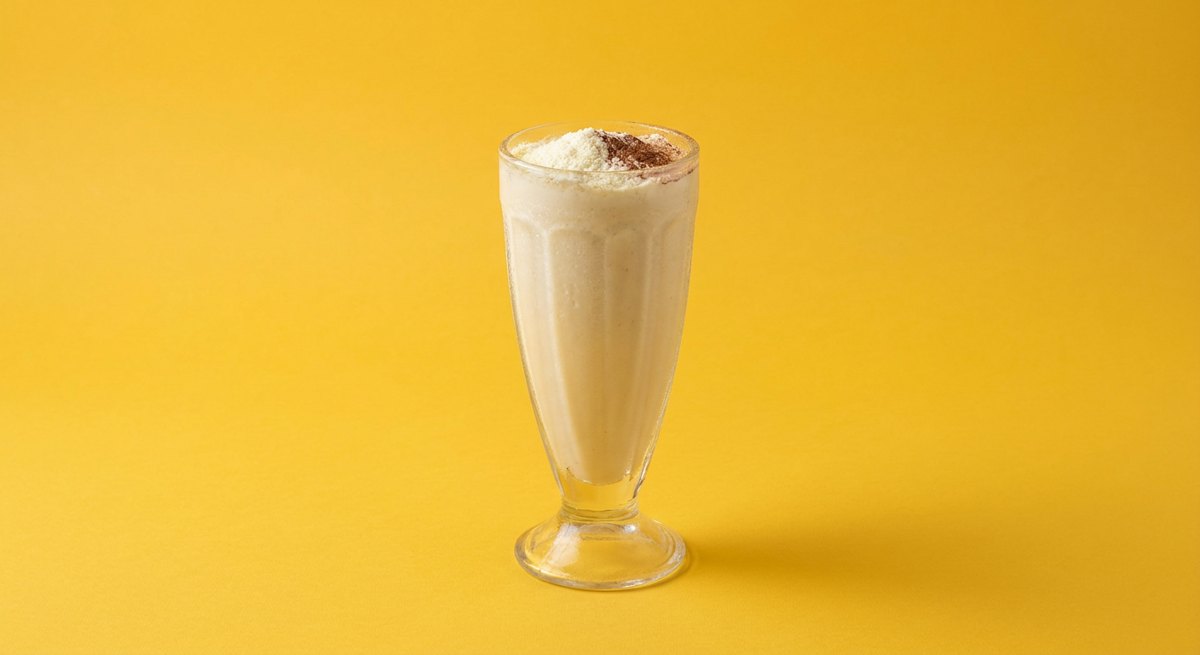 Milkshake de Leite Ninho em copo de vidro, fotografia frontal com fundo colorido