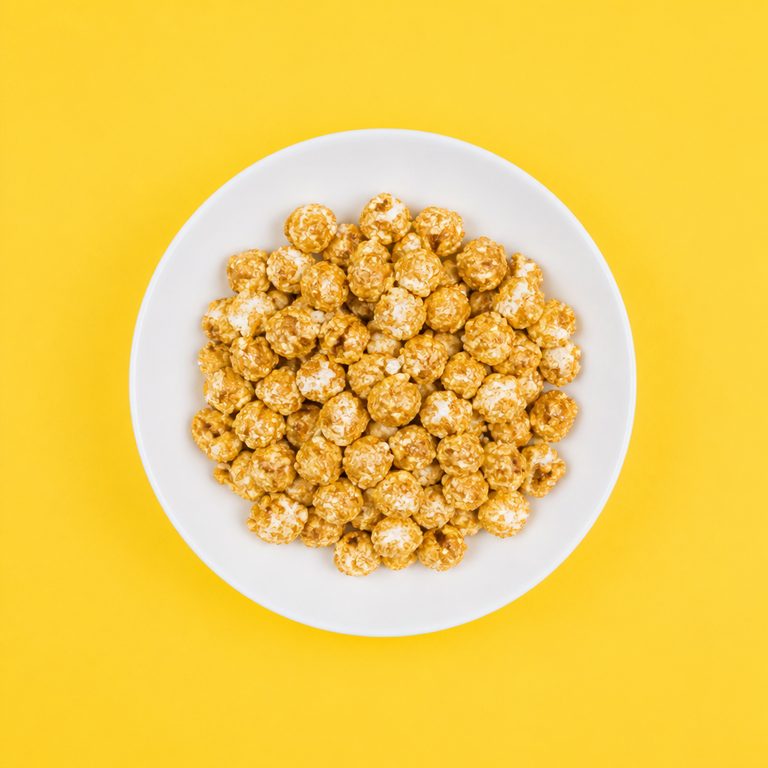 Pipoca Doce Caramelizada em prato branco, fotografia de cima com fundo colorido