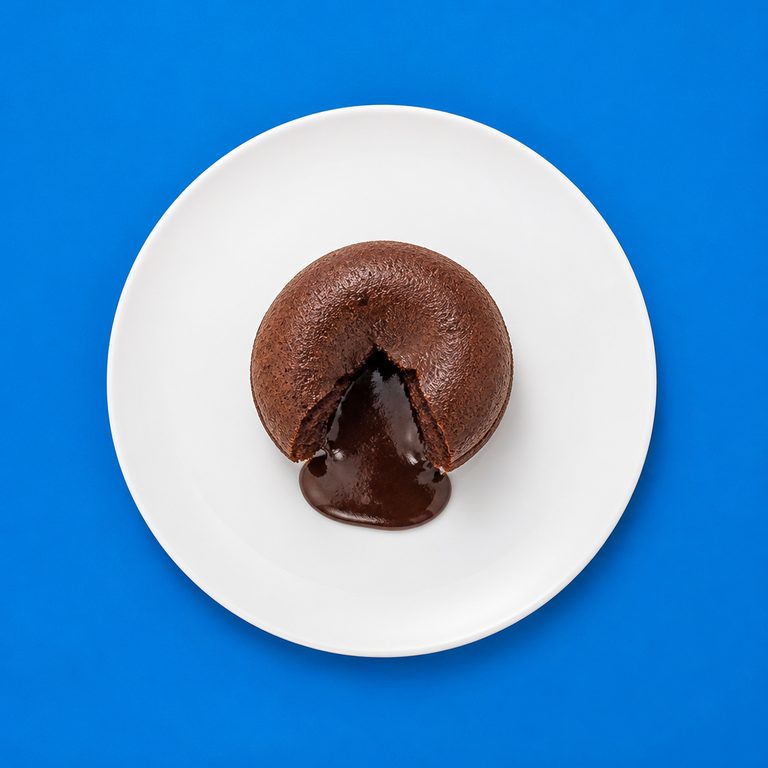 Vulcão de Chocolate em prato branco, fotografia de cima com fundo colorido