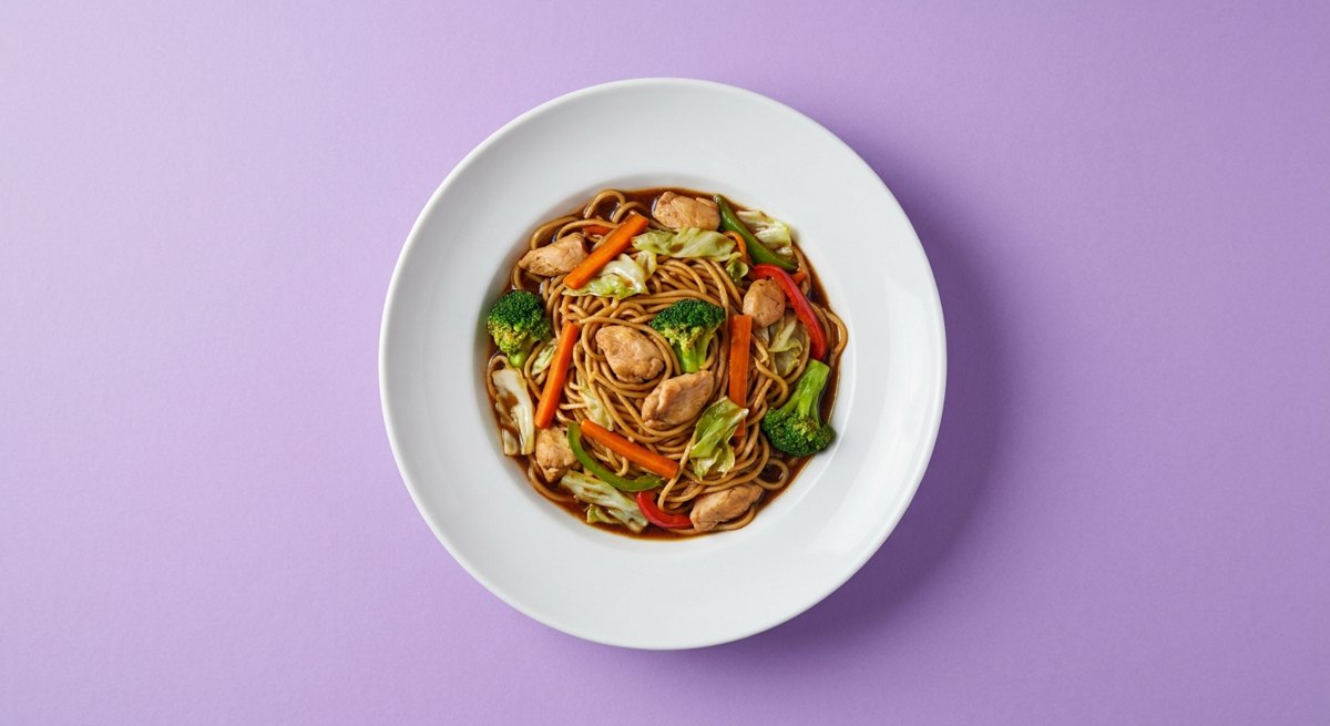 Yakisoba Super Fácil em prato branco, fotografia de cima com fundo colorido